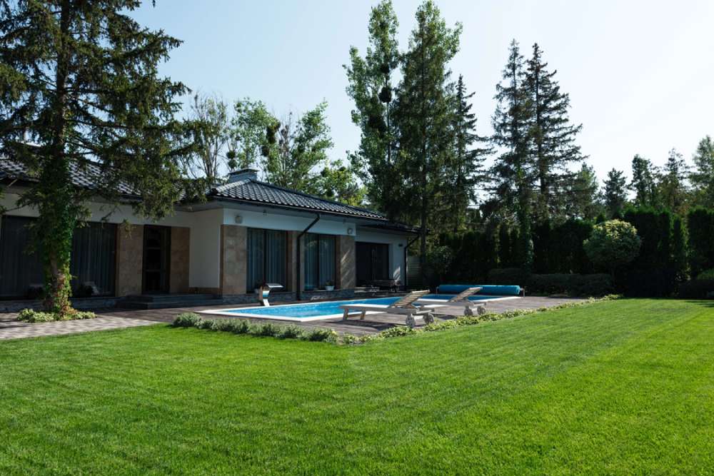 Texte alternatif de l’image	Vue extérieure de la maison moderne, pelouse verte et bord de piscine.